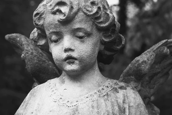 sculpture of an gold angel with dark background