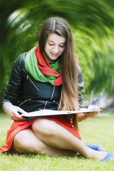 Girl student learning on the grass in the park (education, self-development, self-organization, time management)