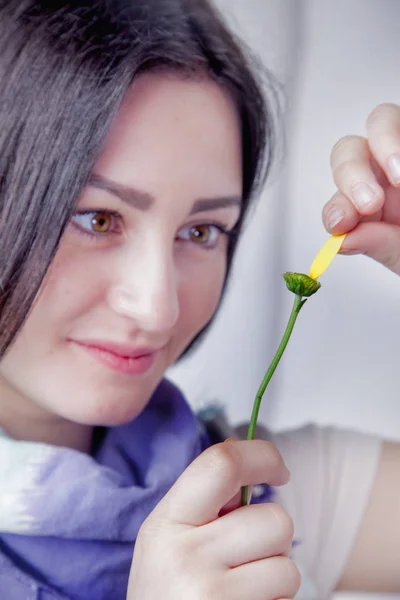 Guessing on a flower. Portrait of beautiful young woman wondering on flower likes or dislikes.