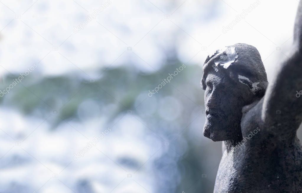 An ancient statue of the crucifixion of Jesus Christ in profile (religion, faith, death, suffering, immortality, God concept)