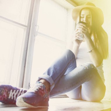 Güzel bir genç kadının bir fincan kahve yakınındaki eski bir vintage penceresi.