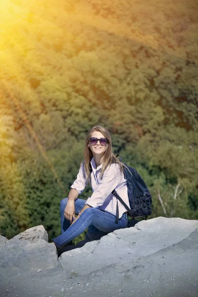 山の頂上に座っているバックパックと幸せな若い女 勝利概念 — ストック写真