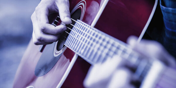 Close up shot of strings and guitarist hands playing guitar. Selective focus on hands.
