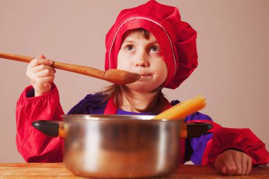 Küçük tatlı kız şef elinde kaşıkla dener