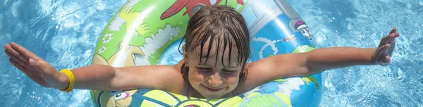 Pequeña niña linda nadando en agua con un anillo colorido. Suma — Foto de Stock