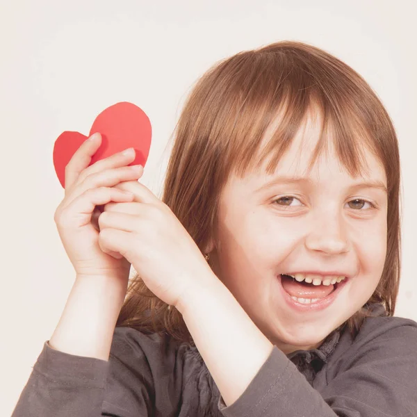 Roztomilé holčička drží červené srdce jako symbol lásky a — Stock fotografie