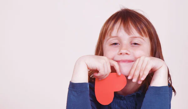 Roztomilé holčička s červeným srdcem jako symbol lásky a štěstí — Stock fotografie