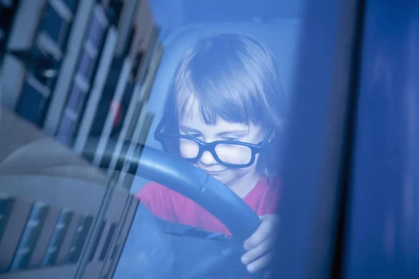 Driving shool. Humorous photo of cute little child girl learns t