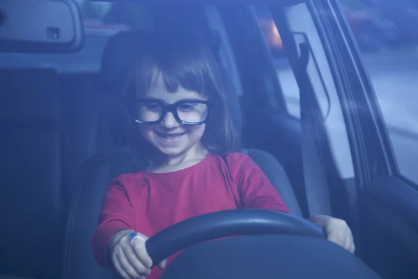 Driving shool. Humorous portrait of cute little child girl learn