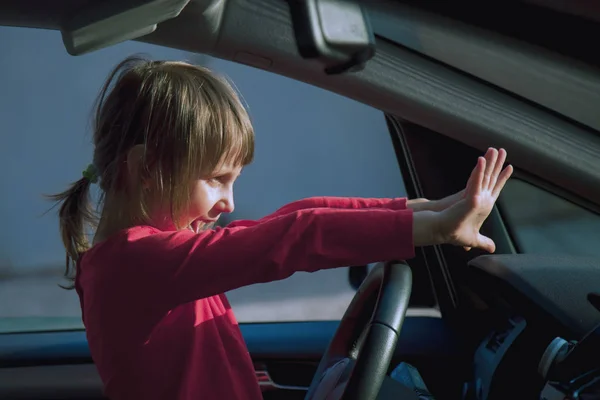 Dangers and risks of underage driving. A little child girl  pani — Stock Photo, Image