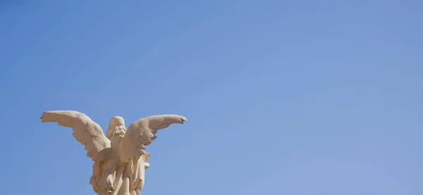 Um anjo com asas contra o céu azul. Estátua antiga. — Fotografia de Stock