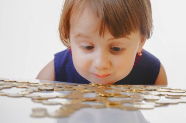 Çocuk kız madeni paraları gelir, kar ve zarar simgesi olarak sayıyor.