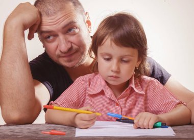 Sabırlı bir babanın portresi kızına evde yardım ediyor.