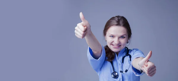Portrét šťastné mladé ženy lékaře se stetoskopem ukazuje f — Stock fotografie
