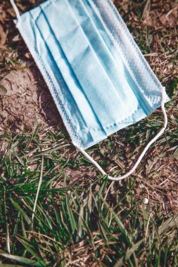 Yüz maskesi çöpü çevre ve doğa için bir tehdit ve tehlike sembolü olarak kullanıldı. Ekolojik felaket, COVID-19, küresel doğa kirliliği. Dikey resim.