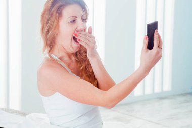 Yatmadan önceki son selfie. Genç ve güzel bir kadın yatakta telefonuyla selfie çekiyor..