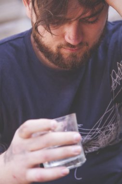 Elinde bir bardak votka tutan adama yaklaş. Alkolizm, acı, bağımlılık kavramının sosyal sorunu.
