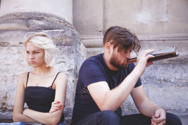 Alkol bağımlılığından dolayı bir erkek ve kadın arasındaki çatışma. Şişeden konyak içen yakışıklı bir adam. Alkolizm, saldırganlık, aile kavgası kavramı. 