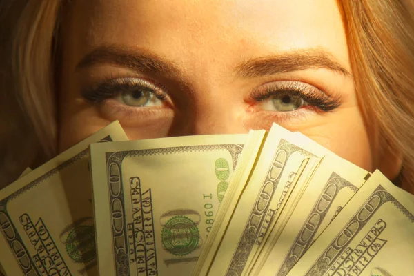 Money is best motivation. Close up portrait of young beautiful woman with US Dollar bills for eyes.