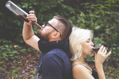 Alkolizm ve alkol bağımlılığı insanlar konsepti. Birbirine aşık bir çift açık havada brendi içiyor..