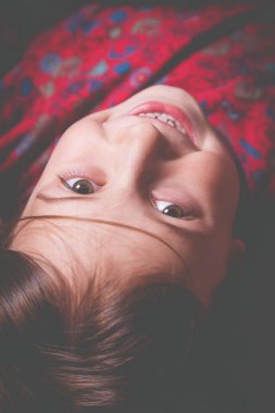 Yatakta eğlenen ve uykuya dalmak istemeyen seksi, hareketli küçük bir kız manzarası. Çocuğun komik yüz ifadesi.