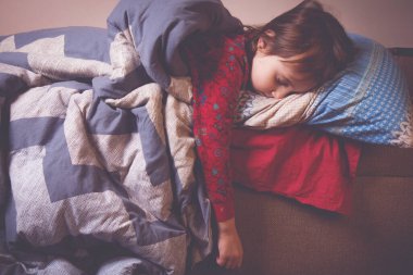 Küçük tatlı kız battaniyenin altında yatakta uyuyor. Yatay resim.