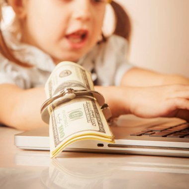 İş kölesi, başarı ve para konsepti. Hırs ve kariyerin sembolü olarak elleri kelepçeli kişileri dizüstü bilgisayarında ABD Doları banknotlarıyla kapat. Seçici para odaklı.