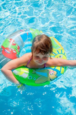 Yüzme havuzunda su sıçratan ve boş zamanlarında eğlenen güzel bir kız çocuğu. Yatay görüntü. Dikey resim.