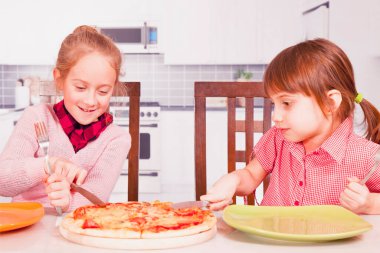 Pizzaya bayılırız! İki küçük bayan arkadaş pizzayı çatal ve bıçakla kestiler..