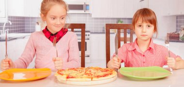 Pizzaya bayılırız! Tatlı küçük kızlar pizza yiyen en iyi arkadaşlar. Yatay resim.