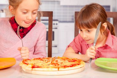 Pizzaya bayılırız! Pizza yiyen şirin küçük kızlar. Yatay resim.
