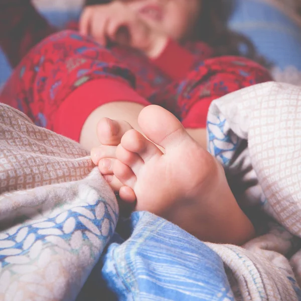 小さな子供の女の子がベッドで寝ている 毛布の上で足を閉じて — ストック写真