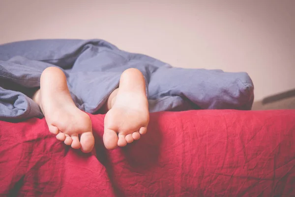 小さな子供の女の子がベッドで寝ている 睡眠とリラックスの象徴として毛布の下の足 — ストック写真