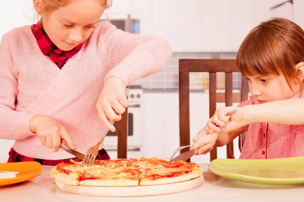 Két Kis Barátnő Késsel Villával Vagdossa Pizzát Boldog Gyerekek Élvezik — Stock Fotó