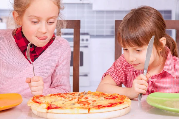 We love pizza! Cute little girls best friends eating pizza.