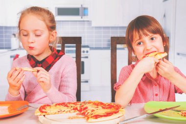 Afiyet olsun! En iyi yiyeceklerin sembolü olarak ellerinde pizza dilimleri olan küçük şirin kızların portresi. Yatay resim.