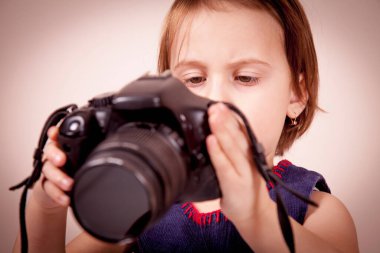 Küçük tatlı kız fotoğrafçı DSLR kamerasının ekranına bakıyor. Göze seçici odaklanma.
