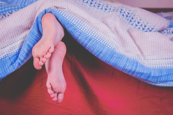 Sleep, rest and relax concept. Little child girl sleeping in bed at home. Close up feet under the blanket.