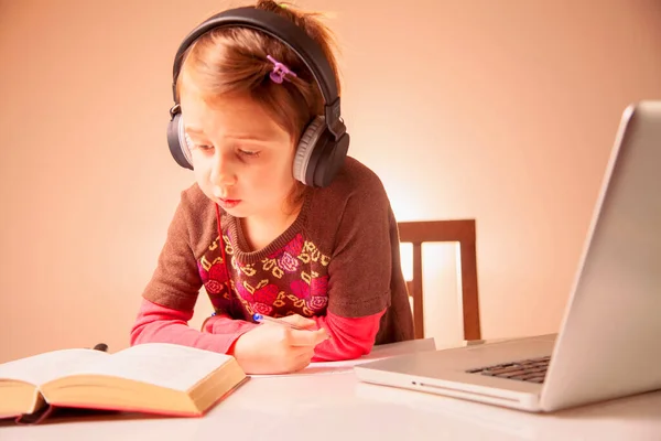 远程在线教育 年轻可爱的女学生戴着耳机在家学习 用笔记本电脑做作业 — 图库照片