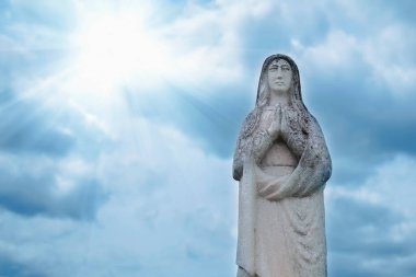 Mavi gökyüzüne karşı Bakire Meryem 'in antik taş heykeli. 