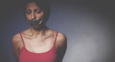 Acı, şiddet kavramı. Ağzı alçıyla kaplı depresif bir genç kadının psikolojik portresi. Tasarım veya metin için boş kopyalama alanı.