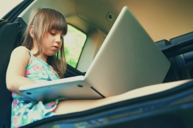 Arabada dizüstü bilgisayar kullanan genç ve güzel bir kız. Uzak çalışma ve iş konsepti.