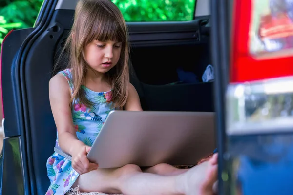 Learn always and everywhere concept. Young beautiful girl sitting in the car and using laptop.
