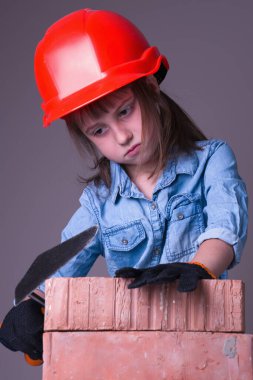 Hayalindeki inşaat projesini yapan sevimli küçük kız müteahhidin esprili görüntüsü. Dikey resim.