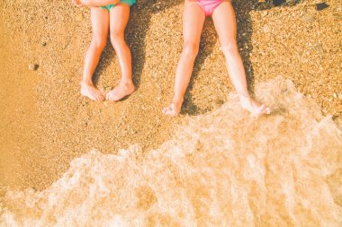 Yaz tatili konsepti. Deniz kıyısındaki kumda çocuk ayaklarının en üst görüntüsü. Yatay resim.