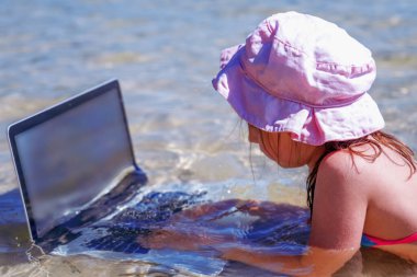 Genç ve güzel bir kızın portresi tropikal denizde dizüstü bilgisayarla uzaktan öğreniyor.. 