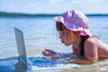 Her zaman ve her yerde çalışma kavramı. Dışarıda tropikal denizde dizüstü bilgisayarla çalışan güzel bir iş kadınının komik portresi. Yatay resim.