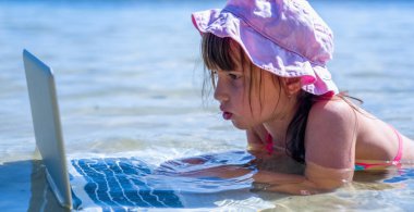 Her zaman ve her yerde çalışma kavramı. Dışarıda tropikal denizde dizüstü bilgisayarla çalışan güzel bir iş kadınının komik portresi. Yatay resim.