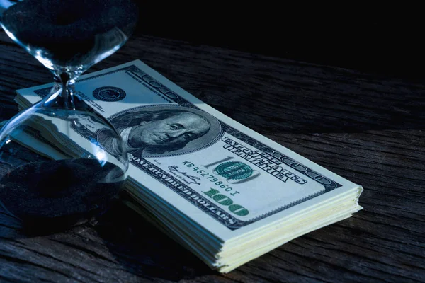 İş için en iyi zaman. Bir kum saati ve Amerikan dolarları. Seçici odaklanma. Yatay resim.