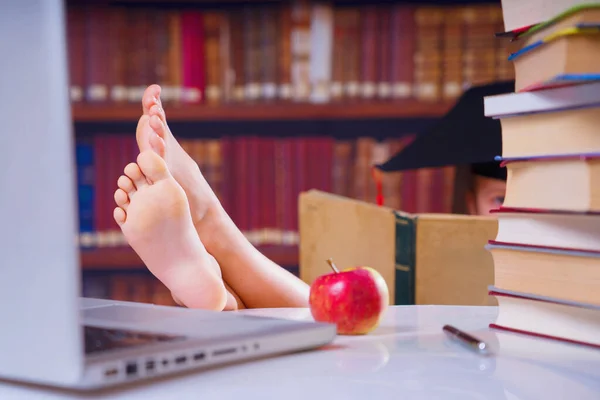 Young beautiful female student reads books. Selective focus on the feet.